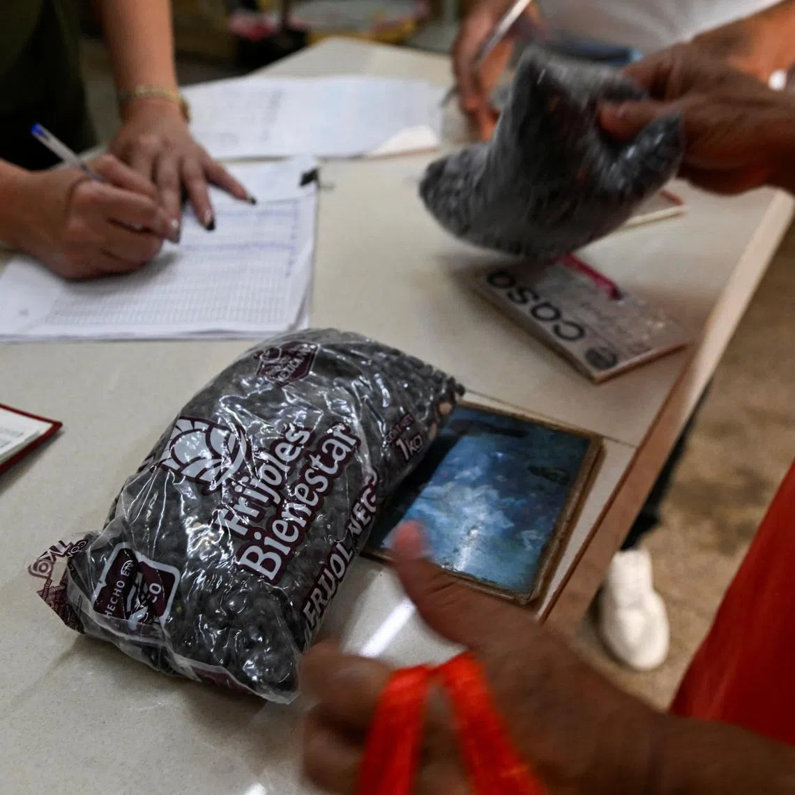 A woman receives beans donated by Mexico, at a subsidized state store, or \"bodega\", in Havana, Cuba March 6, 2026. REUTERS/Norlys Perez