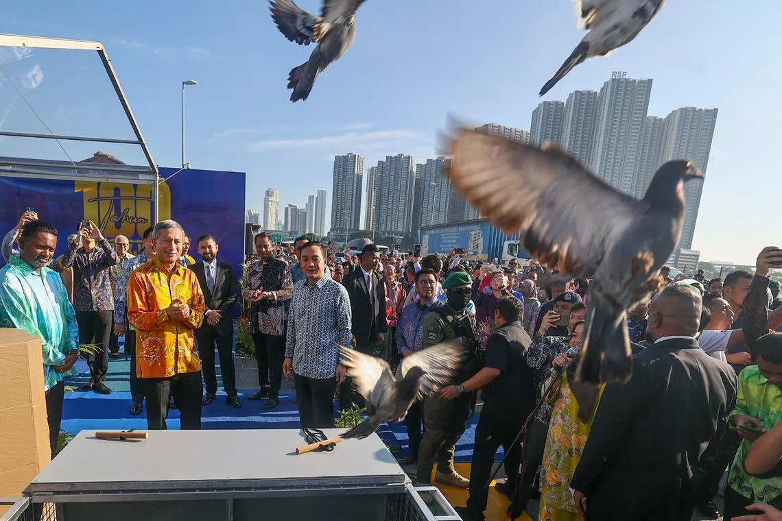 Minister for Foreign Affairs Vivian Balakrishnan (in orange) and Johor Chief Minister Onn Hafiz Ghazi releasing 100 pigeons during celebration ceremony of 100th anniversary of the Johor-Singapore Causeway.