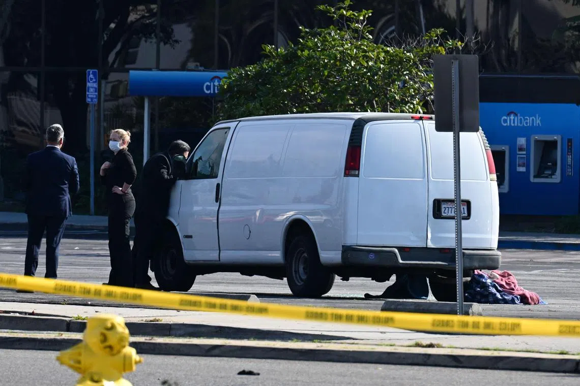 A law enforcement official looks into the window of a van with a body in the driver's seat in Torrance, California, on Jan 22, 2023.