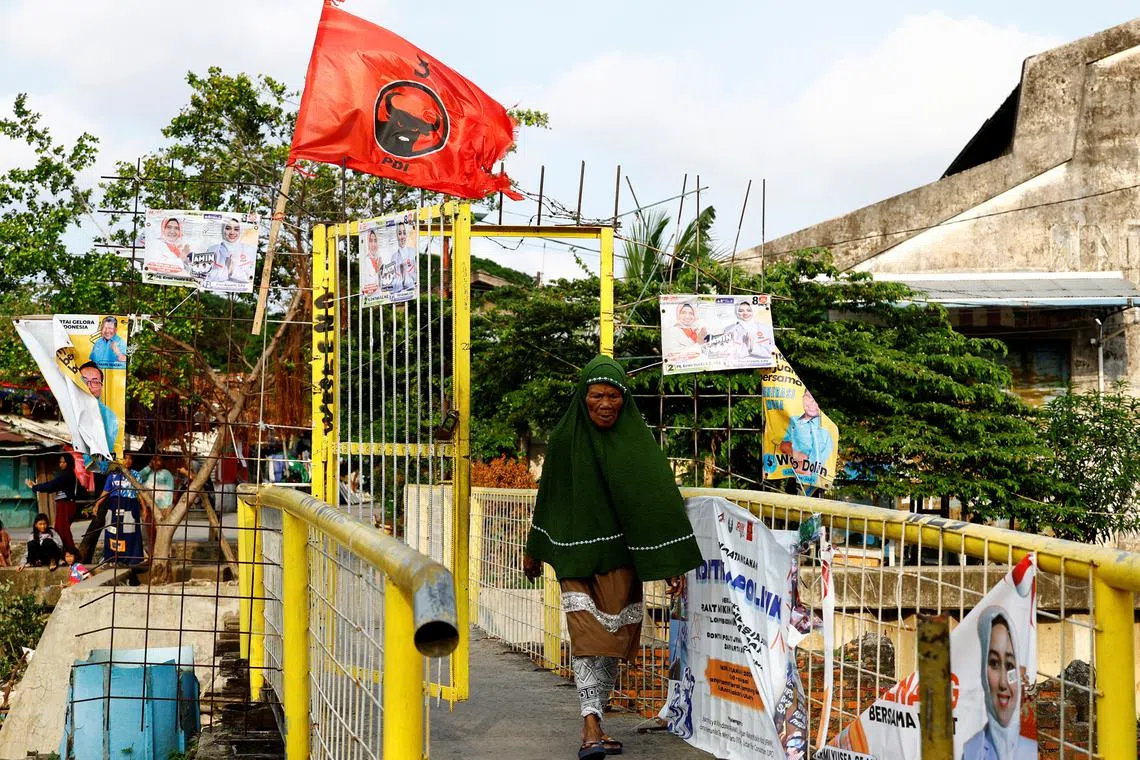 FILE PHOTO: A woman walks past a flag of the ruling Indonesian Democratic Party of Struggle (PDI-P) at a residential area in Jakarta, Indonesia, February 11, 2024. REUTERS/Kim Kyung-Hoon/File Photo