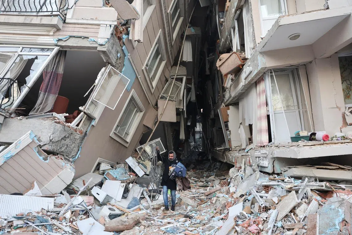 A survivor walks carrying belongings salvaged from his destroyed home, in the aftermath of a deadly earthquake in Hatay, Turkey Feb 9, 2023. 
