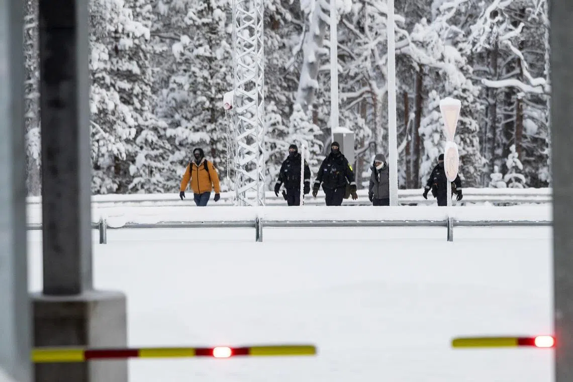 Asylum seekers are accompanied by Finnish border police as they arrive at the Raja-Jooseppi border station in Lapland, northern Finland.