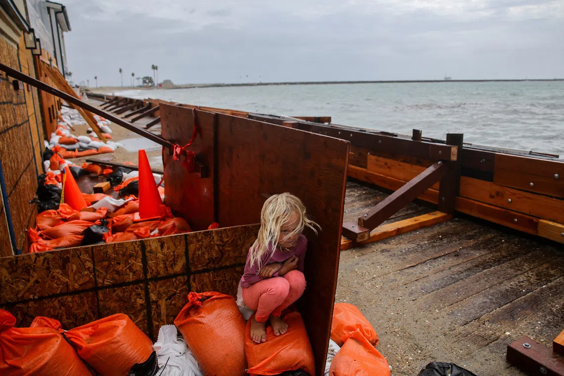 A girl takes shelter from sea spray as Post-Tropical Cyclone Rachel impacts the coastline in Long Beach, California, US, October 11, 2026. REUTERS/Daniel Cole TPX IMAGES OF THE DAY