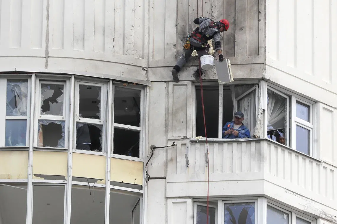 Workers repair a damaged residential building, following a reported drone attack in Moscow, Russia.