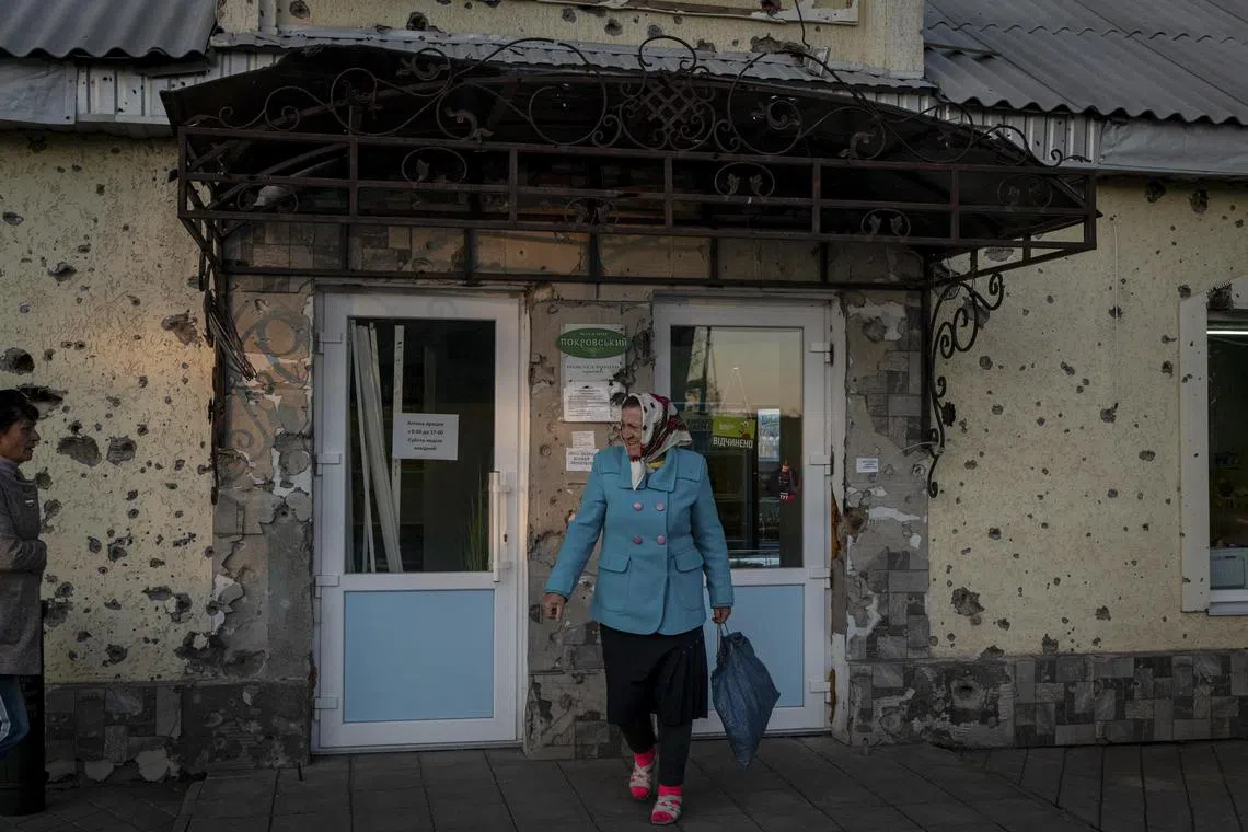 **EMBARGO: No electronic distribution, Web posting or street sales before THURSDAY 12:01 A.M. ET, OCT. 19, 2023. No exceptions for any reasons. EMBARGO set by source.** A resident greets a neighbor outside a shop damaged by shrapnel and bullet holes in Posad-Pokrovske, Kherson region, Ukraine, Oct. 11, 2023. Ukraine’s economy starts to rebound as It adapts to the war; economists predict a return to growth but many challenges lie ahead, including the rebuilding of war-torn cities and labor shortages. (Nicole Tung/The New York Times)