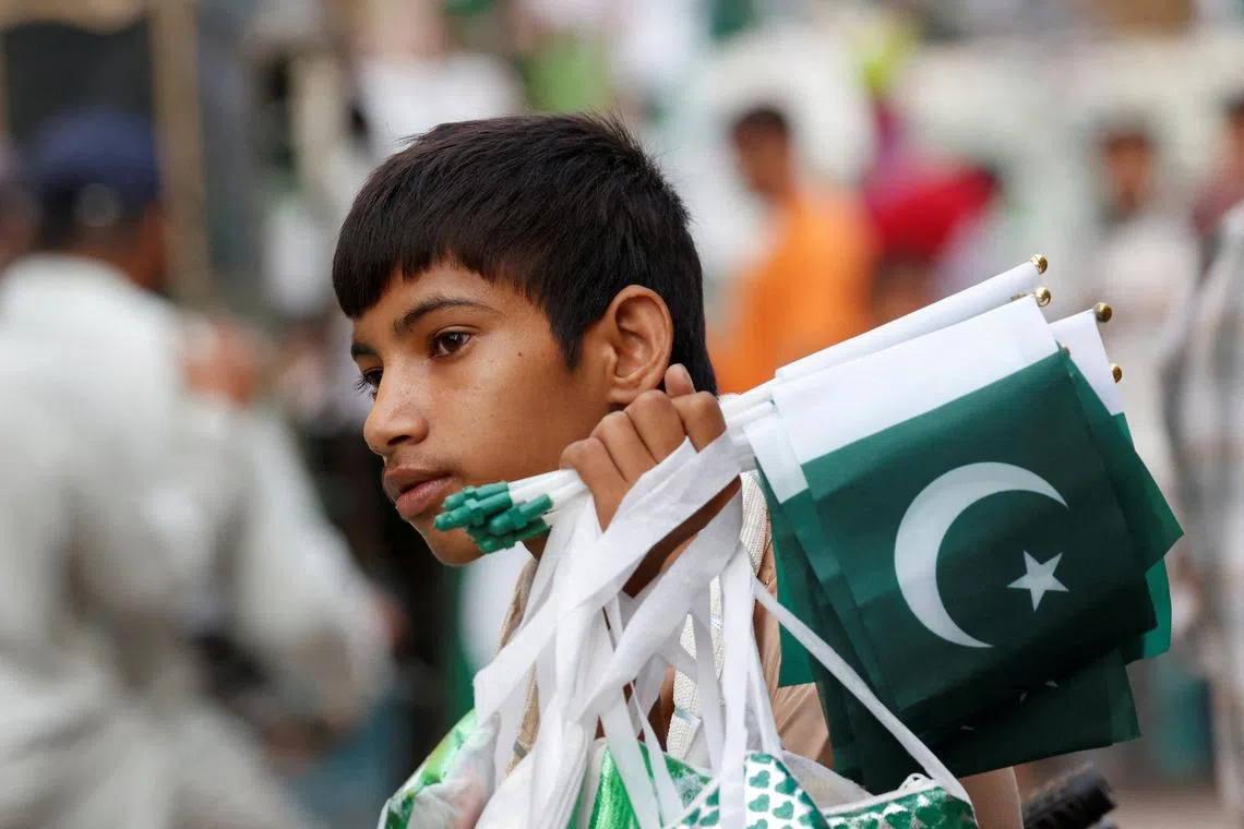 FILE PHOTO: A young man waits for customers, while selling national flags and patriotic memorabilia, ahead of Pakistan's Independence Day, along a market in Karachi, Pakistan August 7, 2024. REUTERS/Akhtar Soomro/File Photo