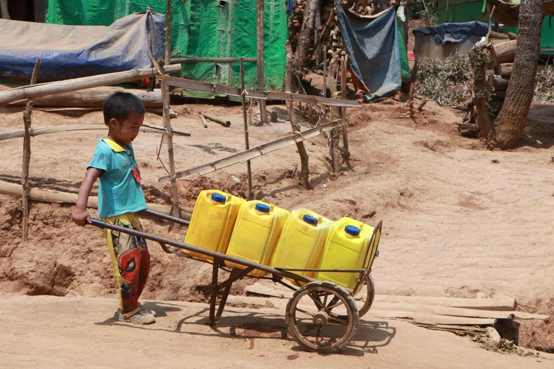This photo taken on April 29, 2024 shows a boy transporting containers for a delivery of drinking water by the charity Clean Yangon at a camp for internally displaced people in Demoso township, in Myanmar's eastern Kayah state. Zay Yar Tun fills up his truck with water for delivery to refugees in the parched hills of war-ravaged eastern Myanmar where a heatwave is adding to the misery of life in displacement camps. (Photo by AFP) / To go with 'MYANMAR-WEATHER-CONFLICT