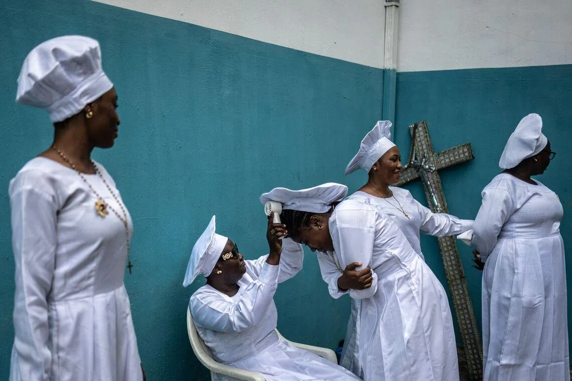 A worshipper using a fan to cool a fellow worshipper inside the compound of the Celestial Church of Christ International Headquarters in the Ketu neighbourhood in Lagos, Nigeria  on May 24, 2026. 