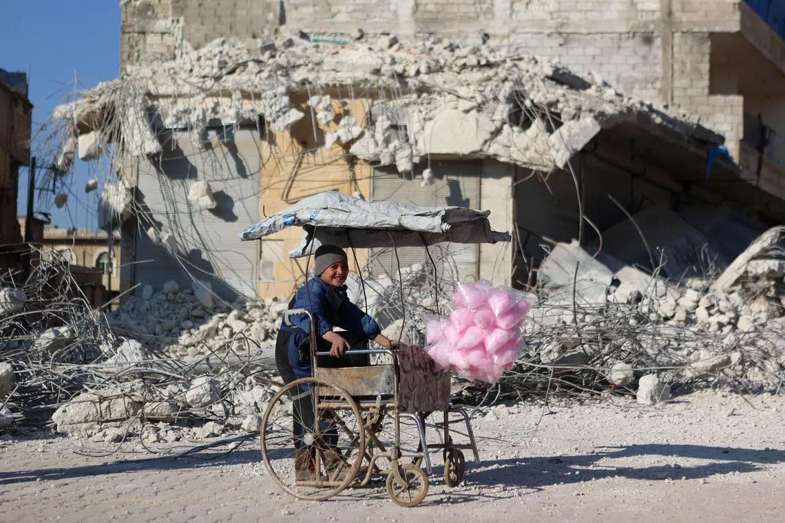 A Syrian child selling cotton candy smiles as he stands in front of the rubble of a collapsed building following last week's earthquake in Syria's rebel-held village of Atarib, in the northwestern Aleppo province, on Feb 14, 2023. More than 35,000 people were killed when the quake devastated swathes of Syria and neighbouring Turkey.