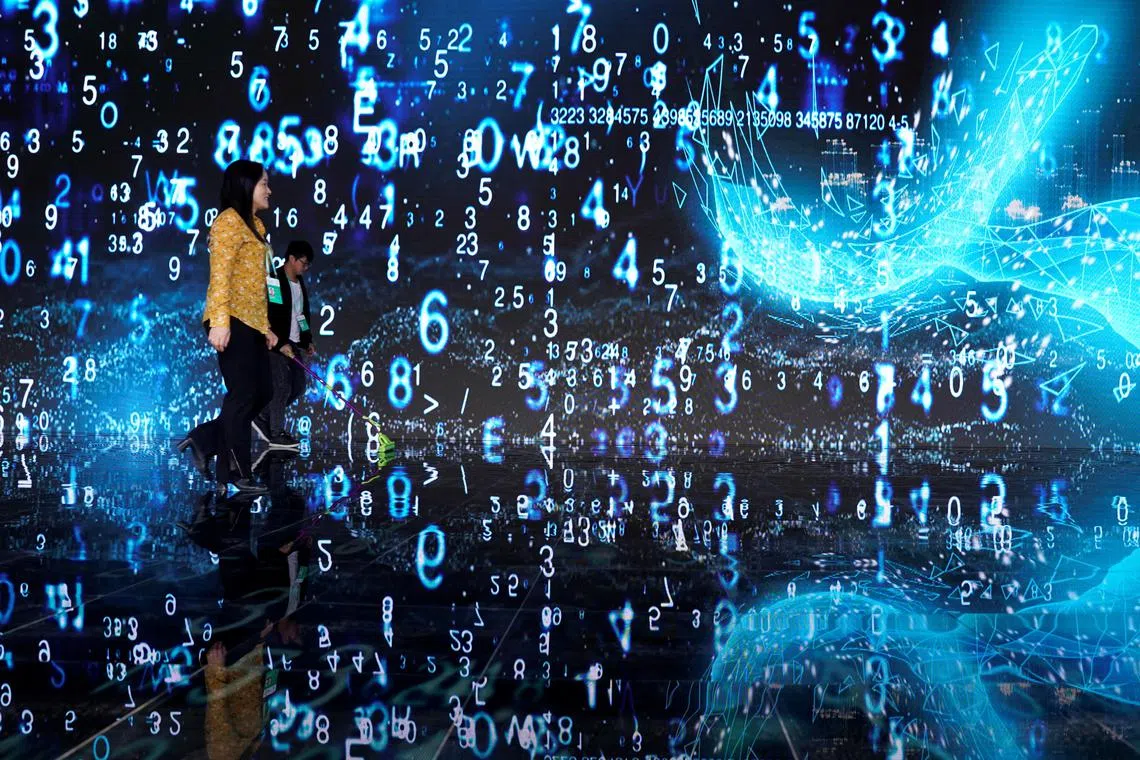 FILE PHOTO: People walks in front of a screen at the World Internet Conference (WIC) in Wuzhen, Zhejiang province, China, October 20, 2019. REUTERS/Aly Song/File Photo