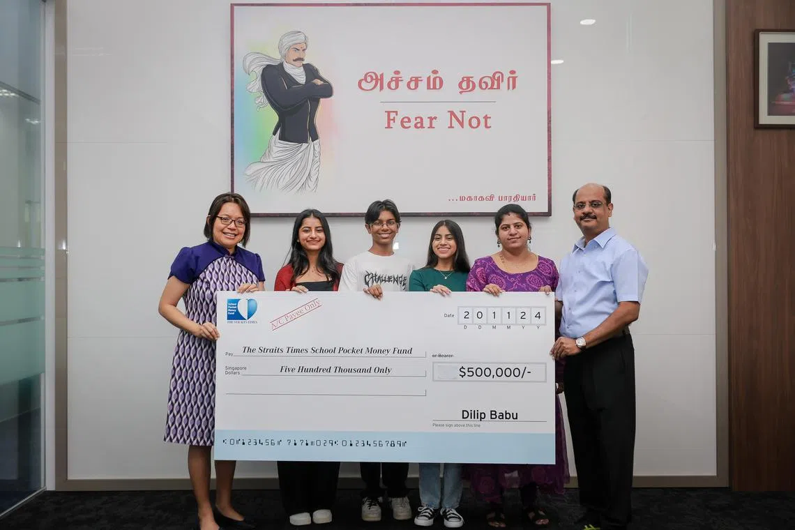 Ms Lee Su Shyan (left), fund trustee and The Business Times associate editor (news), receiving a donation of $500,000 for The Straits Times School Pocket Money Fund from Mr Dilip Babu, CEO of Info-Tech Systems Integrators and JobsLah.com on Nov 20, 2024. With him are (from 2nd right) his wife Ramya, 44, and their children Harini, 16, Arjun, 15, and Srinithi, 20.