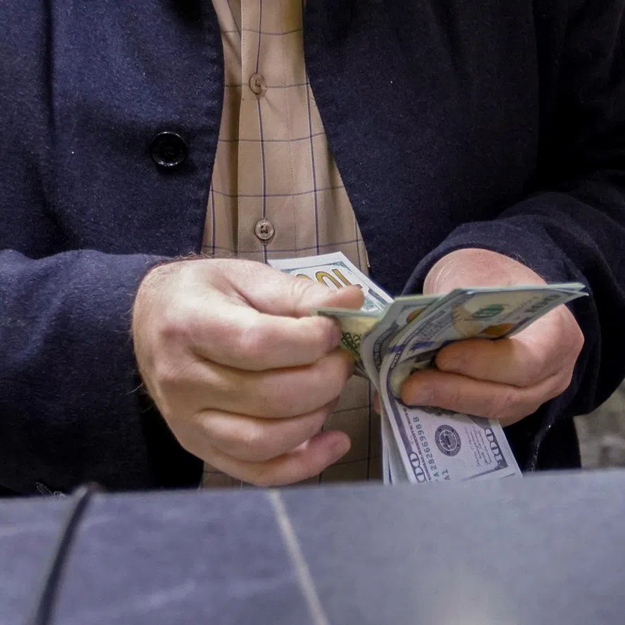 FILE PHOTO: A man counts U.S. dollars at a currency exchange shop in Baghdad, Iraq, January 23, 2023. REUTERS/Ahmed Saad/ File Photo