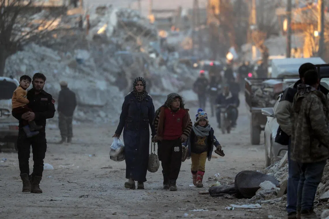 People walk past damaged buildings in the Syrian rebel-held town of Jandaris.