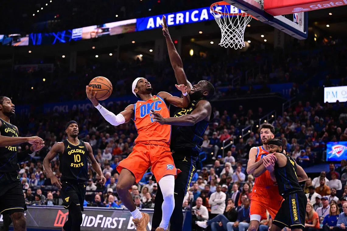 Shai Gilgeous-Alexander of the Oklahoma City Thunder attempts a shot in front of Draymond Green of the Golden State Warriors during the second half at Paycom Center.