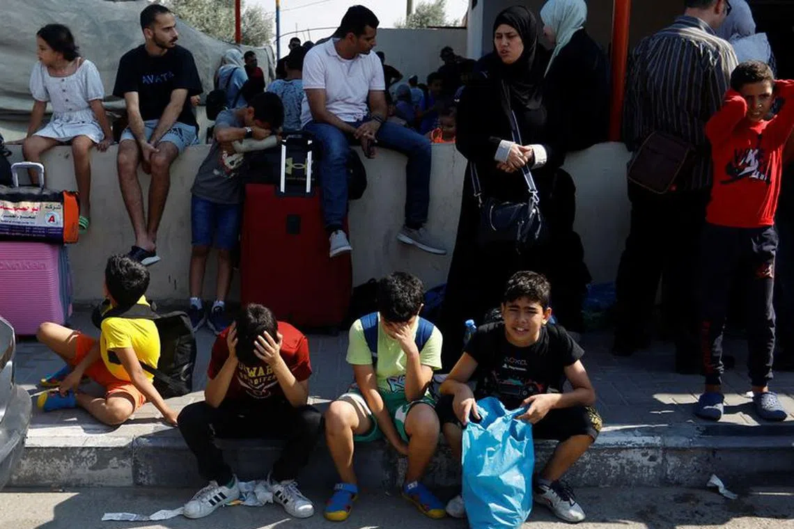 Palestinians with dual citizenship wait outside Rafah border crossing with Egypt in the hope of getting permission to leave Gaza, amid the ongoing Israeli-Palestinian conflict, in Rafah in the southern Gaza Strip October 14, 2023. REUTERS/Ibraheem Abu Mustafa