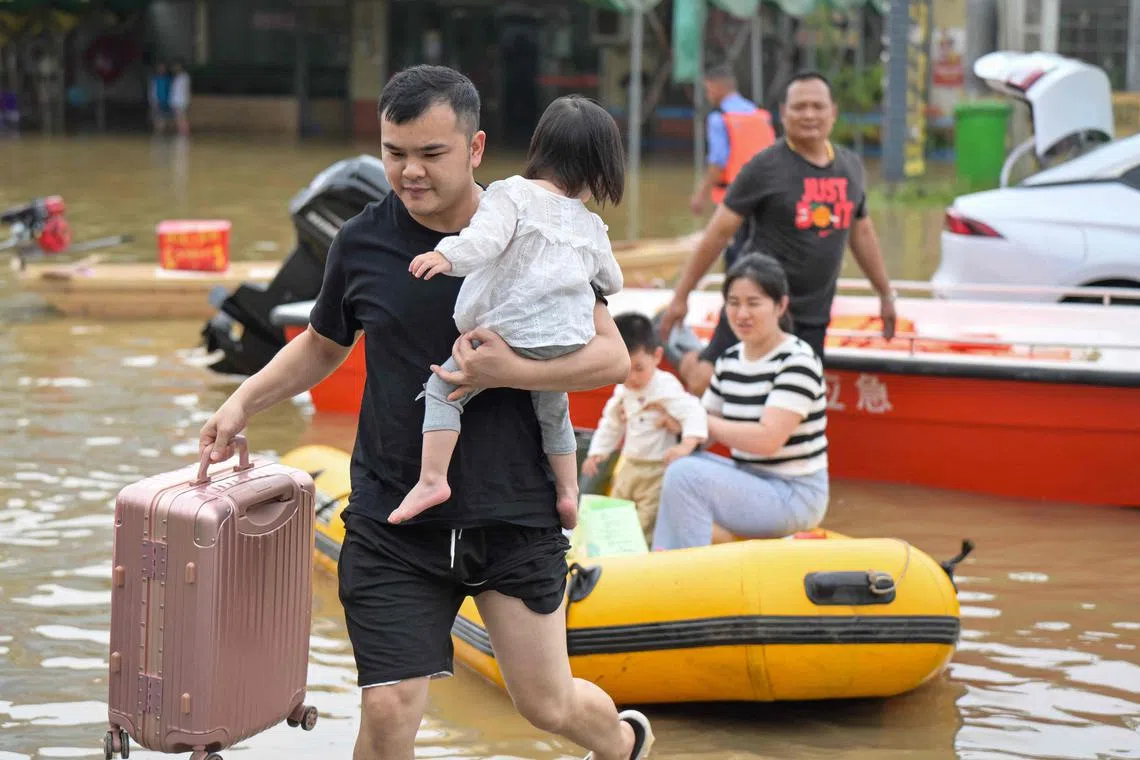 Residents wading through floodwaters after being evacuated from a flooded area following heavy rains in Qingyuan city, in China’s southern Guangdong province on April 22, 2024.