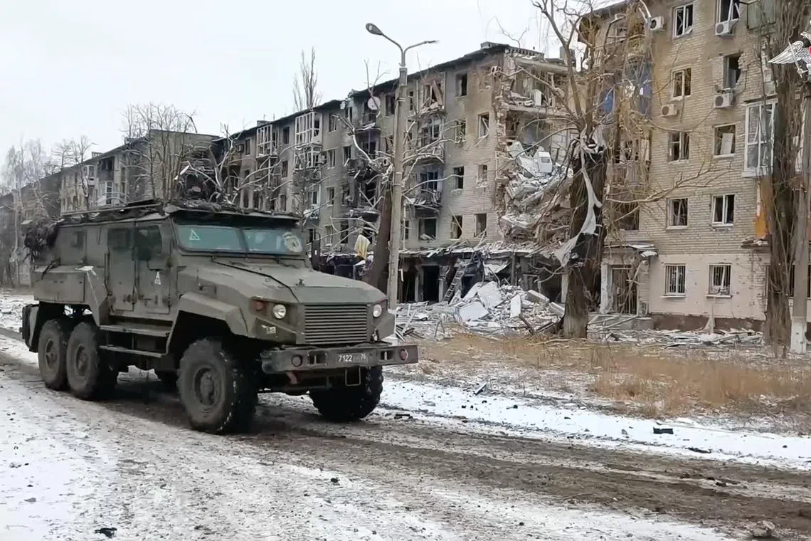 A Russian military vehicle drives past residential buildings damaged in the course of Russia-Ukraine conflict in the town of Avdiivka in the Donetsk region.