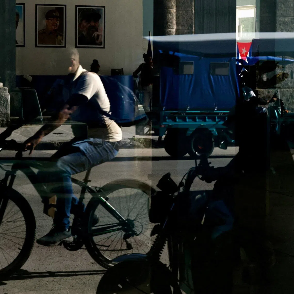 FILE PHOTO: People are reflected in a window of the Central Palace of Computing and Electronics bearing images of late Cuban President Fidel Castro and his brother, former President Raul Castro, who was indicted in the United States in a move that marks an escalation in Washington's pressure campaign against the Caribbean island's communist government, in Havana, Cuba May 20, 2026. REUTERS/Norlys Perez/File Photo