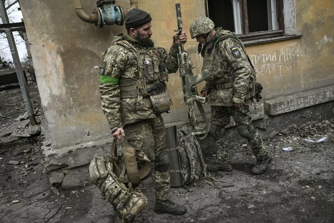 Ukrainian servicemen prepare to join the front-line fighting, near the city of Bakhmut, in Ukraine's Donbas region, on March 11, 2023.