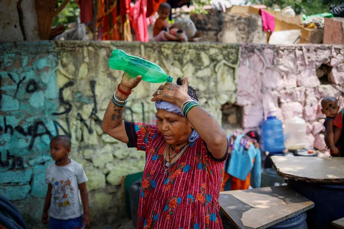 FILE PHOTO: A woman pours water on her head after filling her containers with drinking water from a municipal tanker on a hot summer day in New Delhi, India, May 21, 2024. REUTERS/Adnan Abidi/File Photo