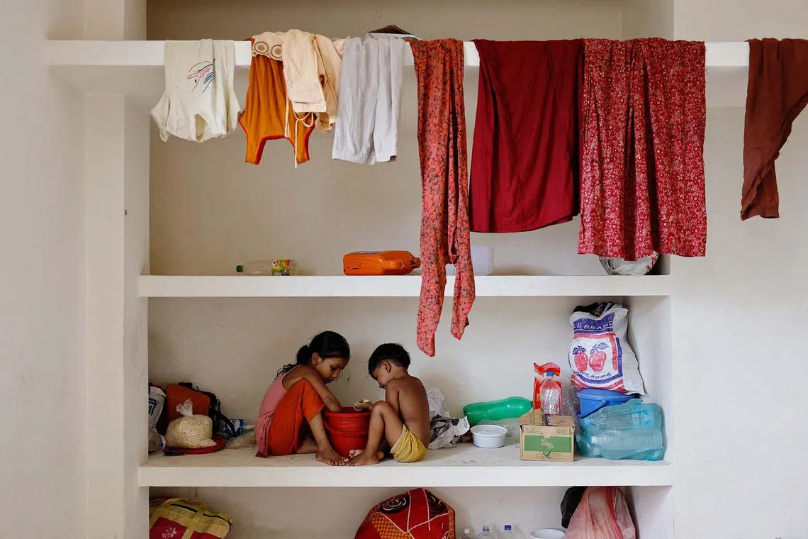 Children eating snacks while sitting on a concrete shelf as they shelter in a madrasa amid severe flooding, in the Fazilpur area of Feni, Bangladesh, Aug 26, 2024. 