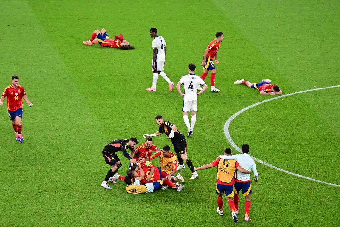 Soccer Football - Euro 2024 - Final - Spain v England - Berlin Olympiastadion, Berlin, Germany - July 14, 2024 Spain players celebrate after the match as England's Declan Rice and Marc Guehi look dejected REUTERS/Angelika Warmuth