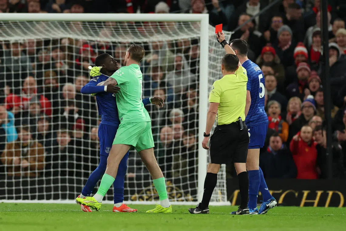 Soccer Football - Premier League - Manchester United v Everton - Old Trafford, Manchester, Britain - November 24, 2025 Everton's Idrissa Gueye is shown a red card by referee Tony Harrington as he clashes with teammate Michael Keane REUTERS/Phil Noble