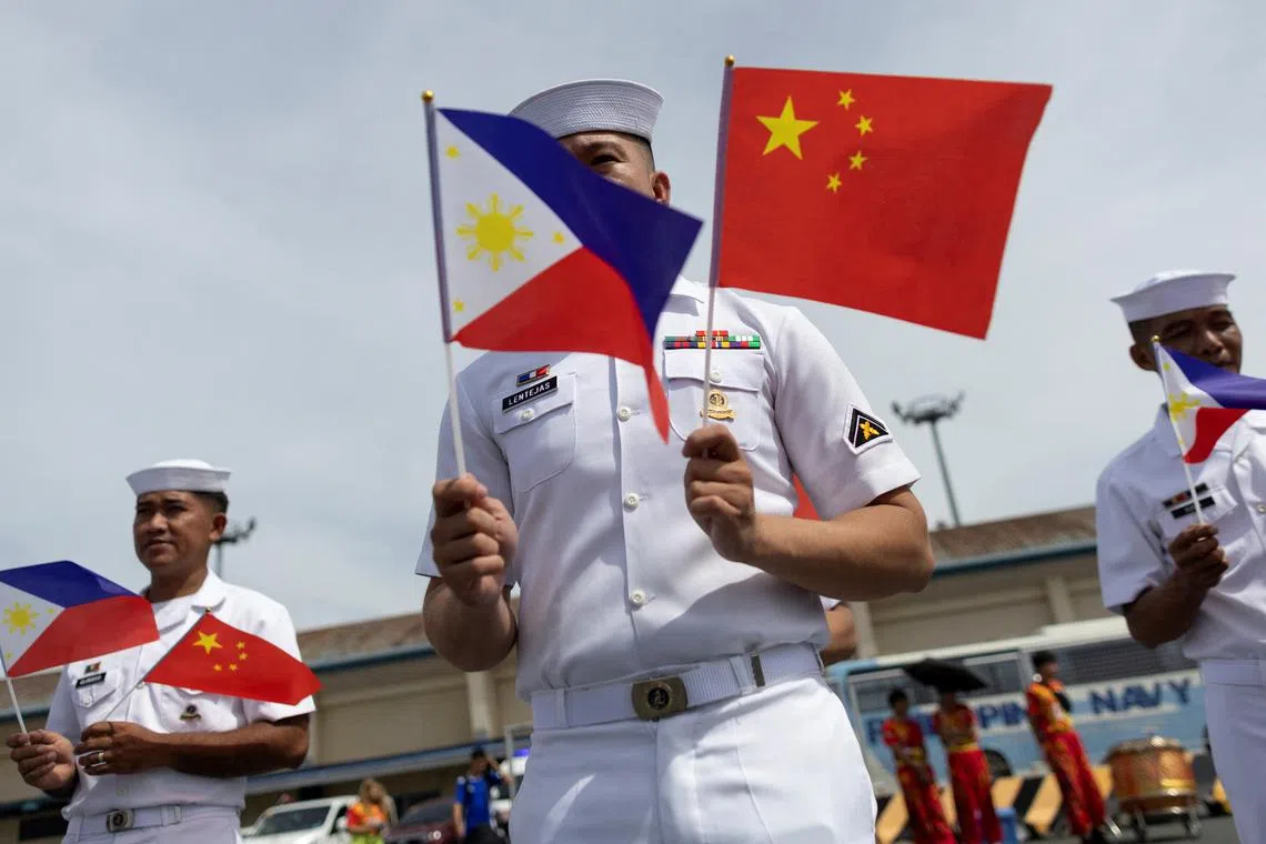 FILE PHOTO: Philippine Navy personnel wave the national flags of China and the Philippines as the Chinese naval training ship \"Qi Jiguang\" docks at the Port of Manila for a four-day goodwill visit, in Manila, Philippines, June 14, 2023. REUTERS/Eloisa Lopez/Files