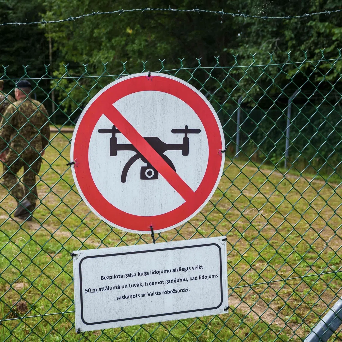 A "No-drone" sign is attached on a fence as soldiers patrol in the area of Piedruja area, on the sidelines of the visit of Latvia's President, who will inspect the border between Latvia and Belarus, on August 17, 2026 in Piedruja, Latvia. (Photo by Gints Ivuskans / AFP)