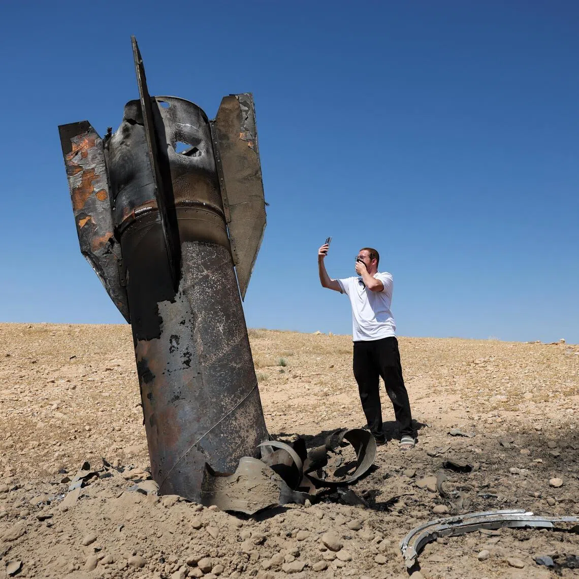 An Israeli takes a photo of the remains of an Iranian ballistic missile.