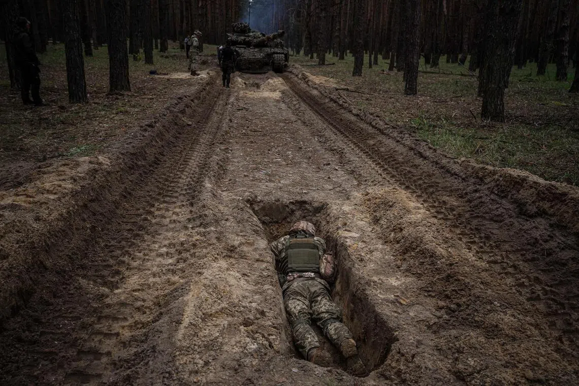 A Ukrainian serviceman laying in a trench during a military exercise in the Kharkiv region on May 1, 2023, amid the Russian invasion of Ukraine. 