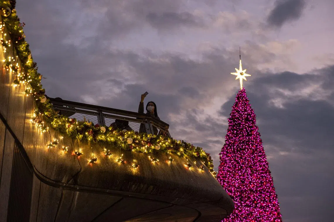 A woman takes a selfie next to a Christmas tree in Hong Kong, China, Dec 12, 2022. The tree and decorations, set in the West Kowloon Cultural District and Victoria Harbour, are part of the Hong Kong WinterFest Christmas Town 2022. 