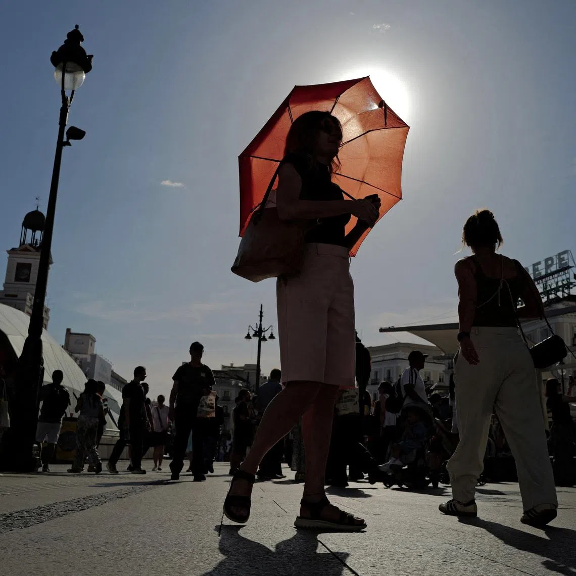 FILE PHOTO: A woman with an umbrella walks at Plaza Puerta del Sol during a spring heatwave in Madrid, Spain, May 27, 2026. REUTERS/Kacper Pempel/File Photo