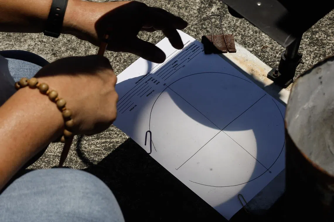 A partial hybrid solar eclipse is reflected on a data sheet with the use of a telescope at an astronomical observatory compound in Quezon City, Metro Manila, Philippines, April 20, 2023. 