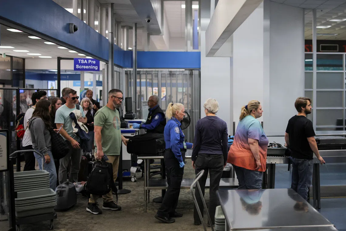 Travelers pass through a Transportation Security Administration (TSA) security screening at Hollywood Burbank Airport during the first day of a partial U.S. government shutdown in Burbank, California, U.S., October 1, 2025. REUTERS/Daniel Cole