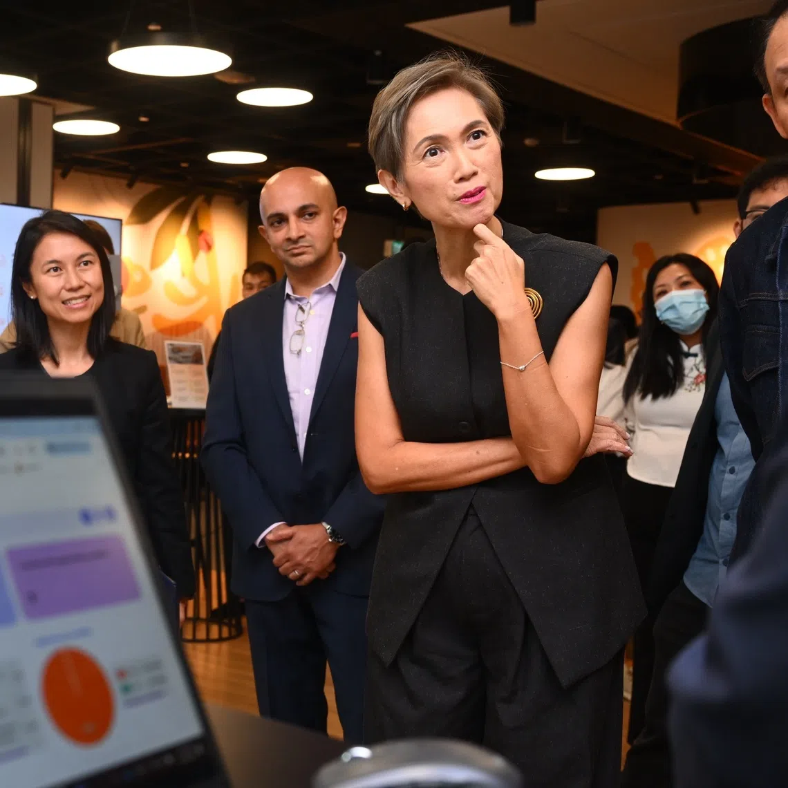 Minister for Digital Development and Information Josephine Teo (second from right) and Senior Parliamentary Secretary for Culture, Community and Youth Goh Hanyan (left) looking at live demonstrations of AI technologies transforming finance and supply chain management at PwC's flagship AI Hub on Aug 11.