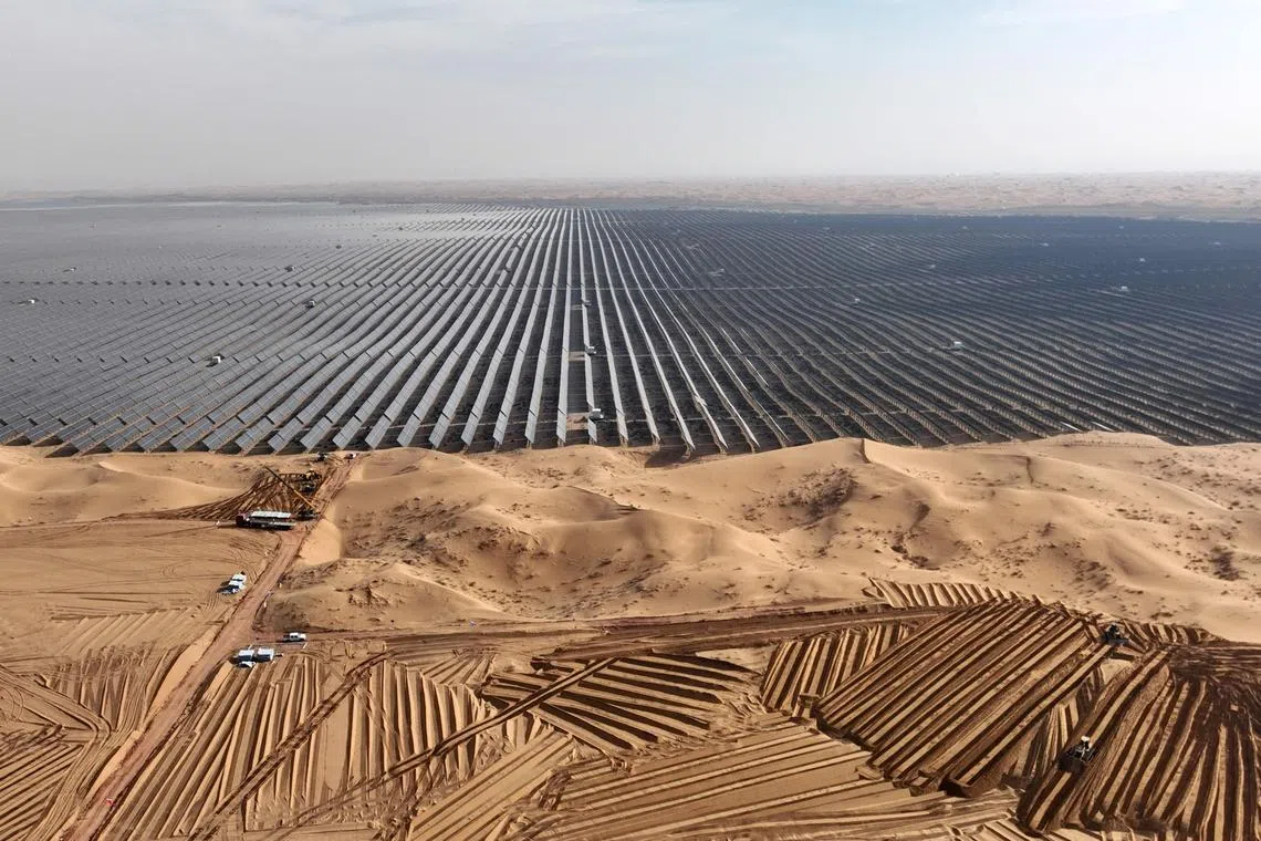 Vehicles prepare land for new solar panels next to a field of solar panels in China's northen Ningxia region on Dec 9, 2023.