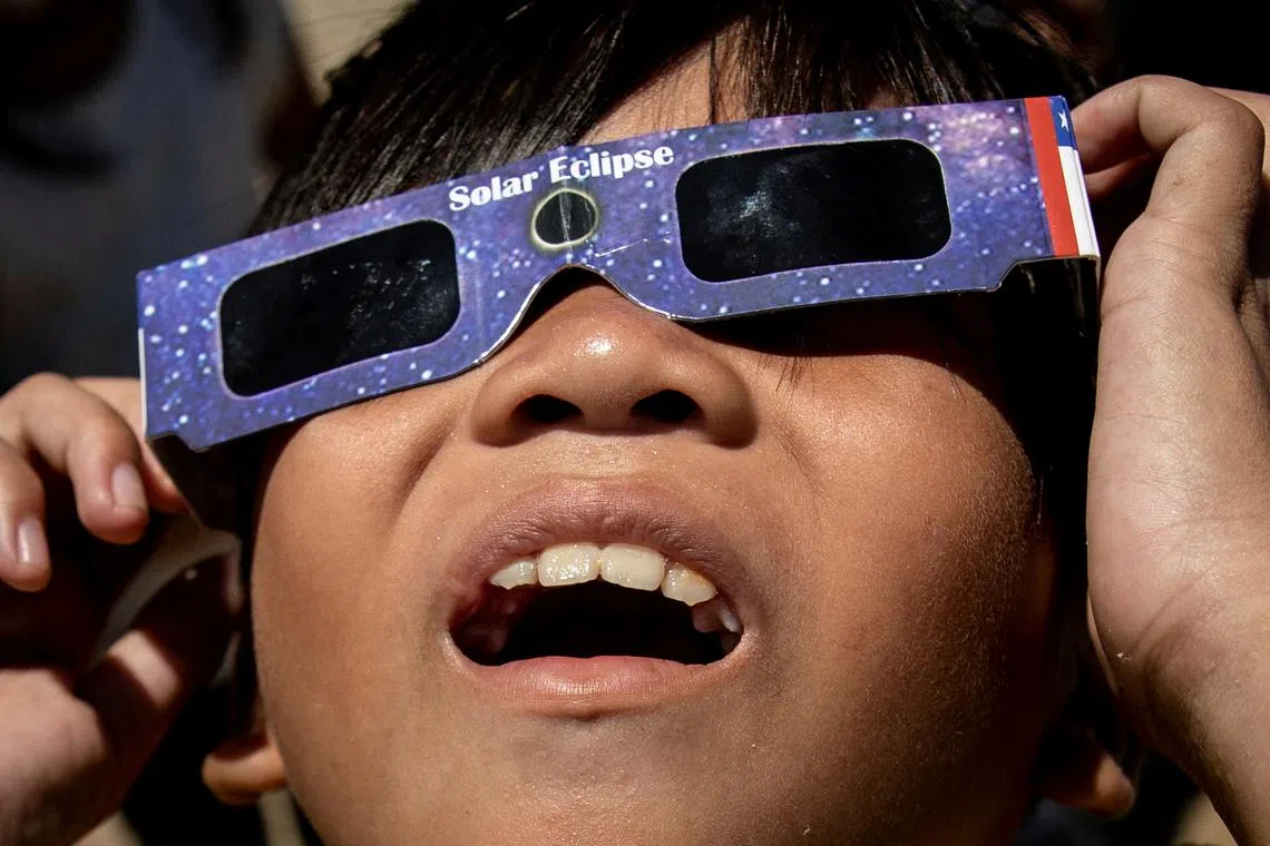 A boy looks at the hybrid solar eclipse with protective glasses, in Marikina City, Metro Manila, Philippines, April 20, 2023. 