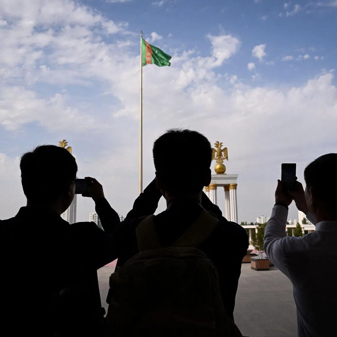 (FILES) The main flag of Turkmenistan sits in front of the State museum of the State cultural centre of Turkmenistan in the capital of Ashgabat on June 28, 2023. Three men who escaped one of the world's most secretive and repressive states have told AFP how they were tortured, beaten and subject to punishment rapes in penal colonies and psychiatric hospitals in Turkmenistan for the "crime" of being gay. When the oil- and gas-rich Central Asian republic makes the headlines, it is usually for the eccentricities of its "National Leader" and "Hero Protector" Gurbanguly Berdymukhamedov. But behind the monumental statues and the marble city of Arkadag built in Berdymukhamedov's honour, opponents and minorities are mercilessly persecuted, say Amnesty and Human Rights Watch, none more so than LGBT+ people. (Photo by Natalia KOLESNIKOVA / AFP)