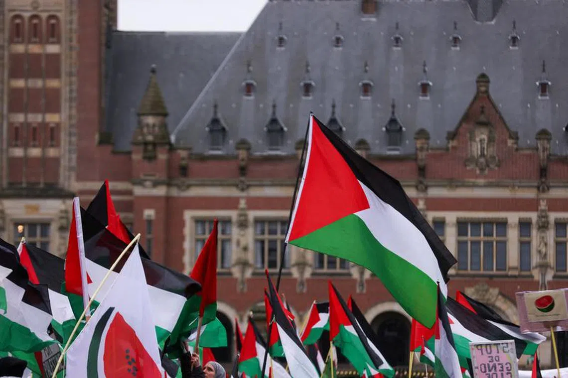 People hold flags as pro-Palestinian protesters gather near the International Court of Justice (ICJ) as judges hear a request for emergency measures by South Africa to order Israel to stop its military actions in Gaza, in The Hague, Netherlands January 12, 2024. REUTERS/Thilo Schmuelgen
