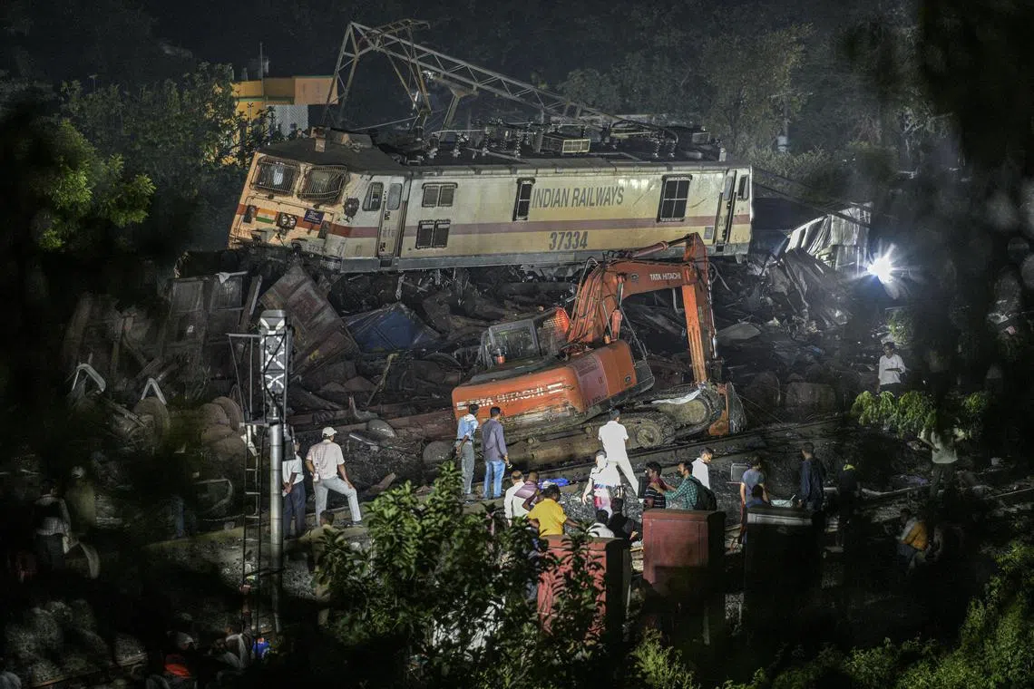 An excavator is used to start clearing the wreckage derailed train coaches from the tracks in Balasore district, in the eastern Indian state of Orissa, Saturday, June 3, 2023. 