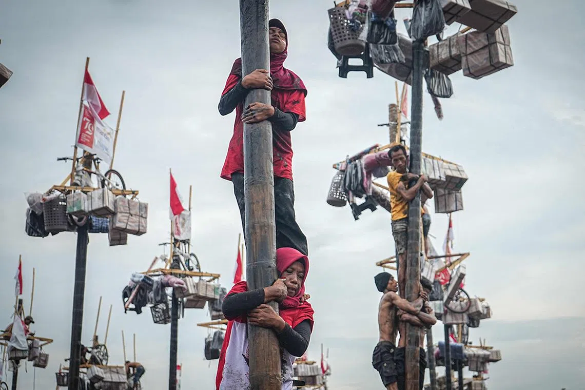 Women participate in a traditional game called "Panjat Pinang" to climb a 4-meter-high tree pole smeared with oil to collect prizes at the top as part of the annual celebration of Indonesia's 79th Independence Day in Palembang, South Sumatra, on August 18, 2024. (Photo by Al ZULKIFLI / AFP)