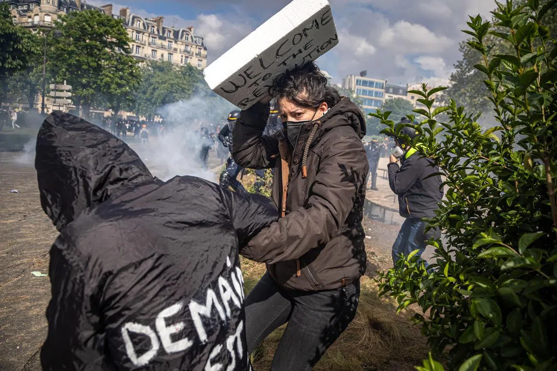 Protesters protect themselves from a police charge, during clashes in Paris over government pension reforms.