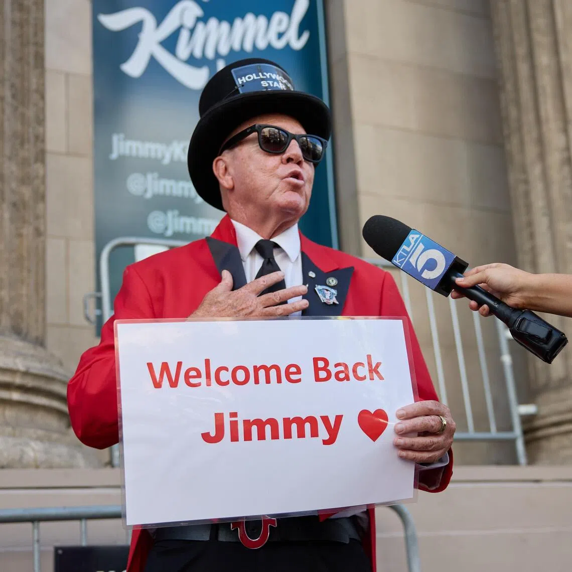 Actor Gregg Donovan is interviewed as he holds a sign welcoming back Jimmy Kimmel in Los Angeles, California.
