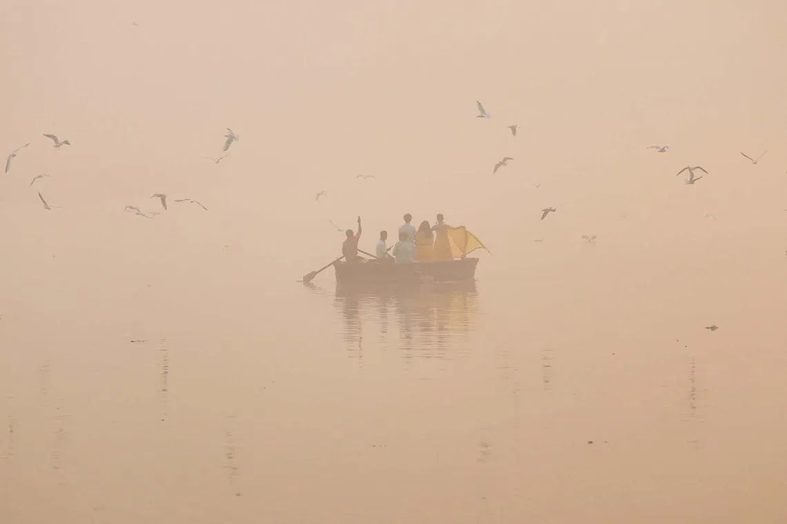 People take pictures on a boat on the Yamuna river on a smoggy morning in New Delhi, India, November 4, 2024. REUTERS/Anushree Fadnavis TPX IMAGES OF THE DAY