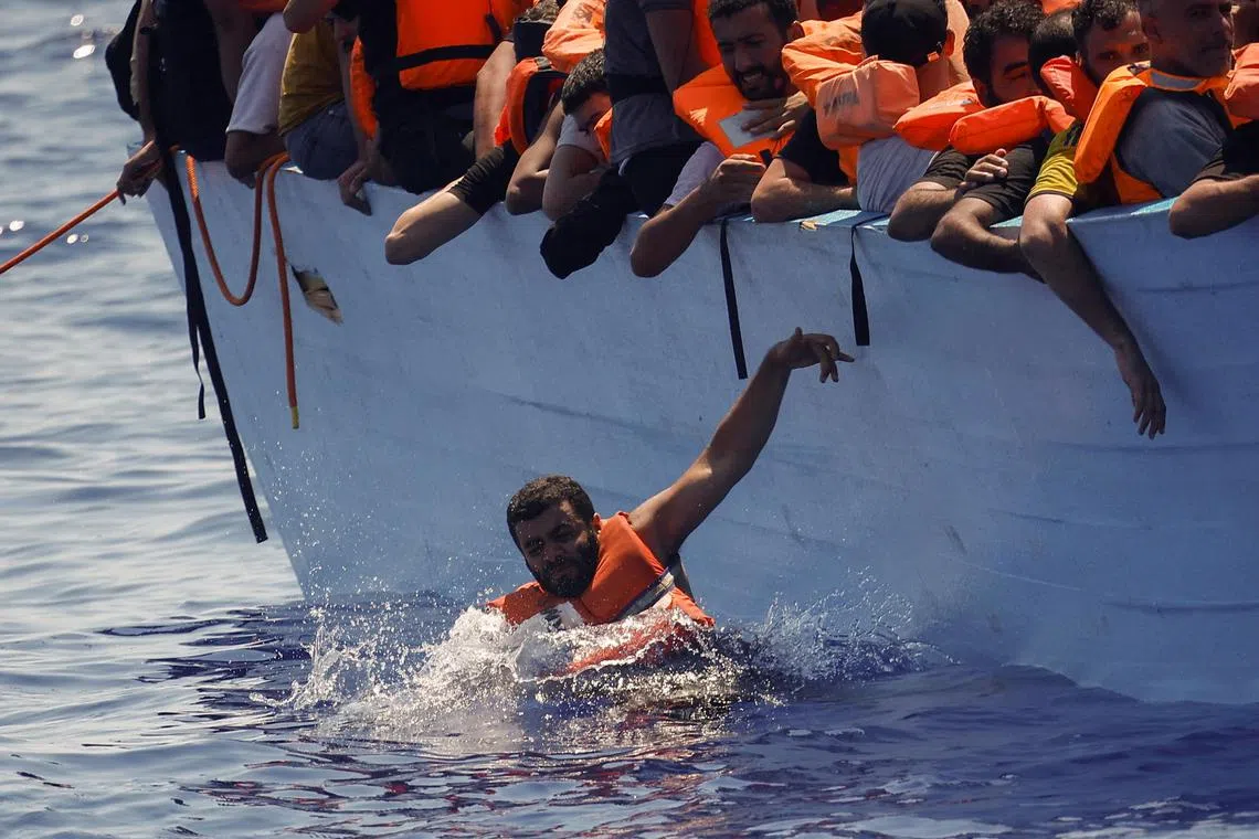 A migrant jumps into the water as a rescue vessel arrives, in international waters south of the Italian island of Lampedusa, in 2024.