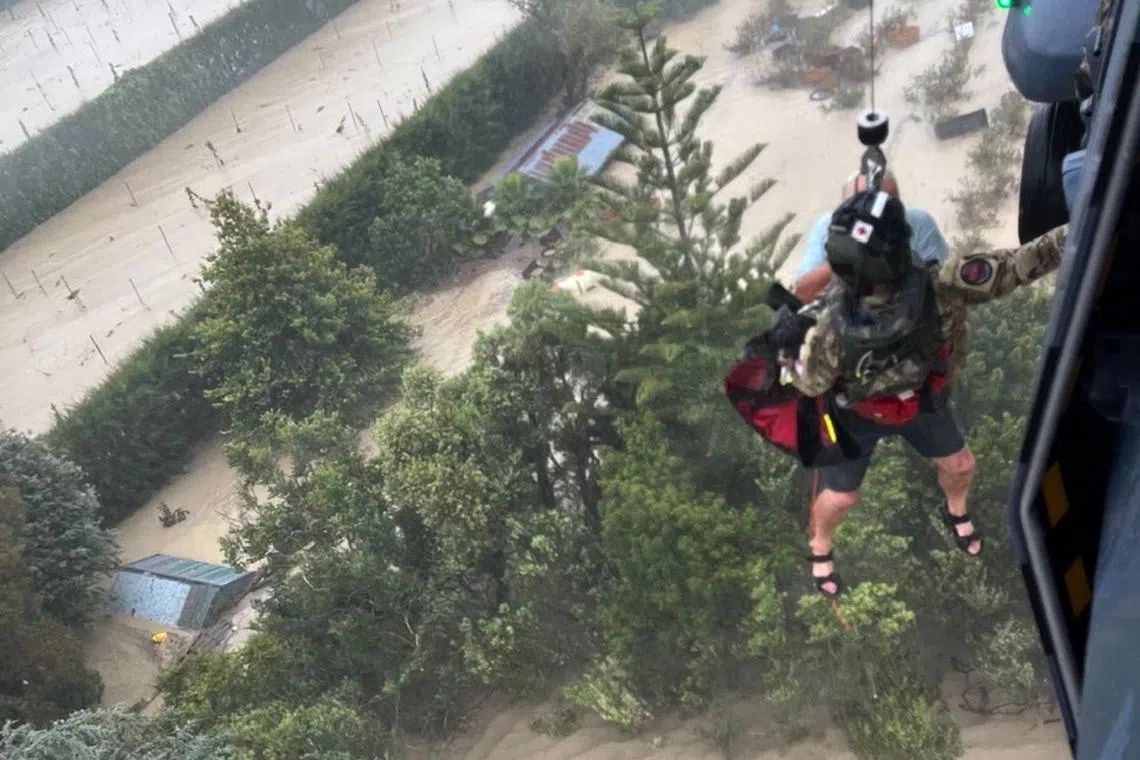 A handout photo taken and received on Feb 14, 2023, from the New Zealand Defence Force shows stranded people being air lifted from their rooftop by a military helicopter in the Esk Valley, near the North Island city of Napier.