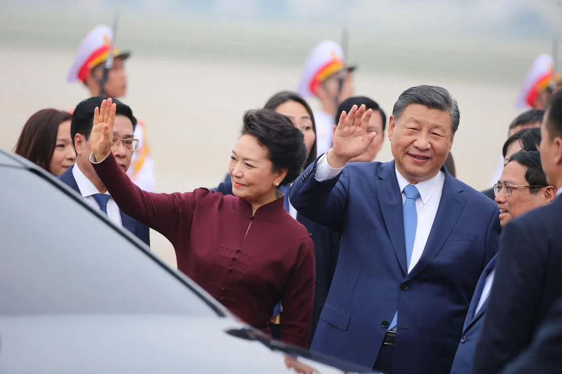 China's President Xi Jinping (R) and his wife Peng Liyuan waved as they arrive at Noi Bai International airport in Hanoi on Dec 12, 2023.  