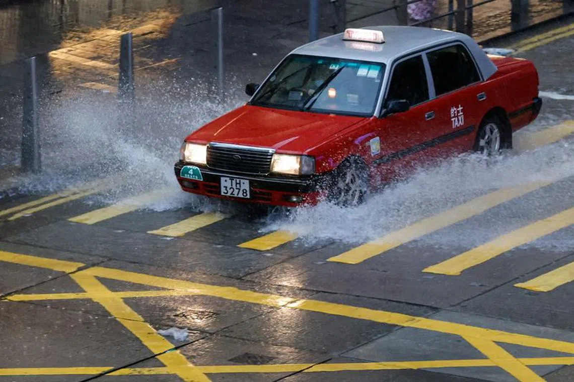A taxi driver drives past a puddle after Typhoon Koinu brings heavy rain to the city, in Hong Kong, China October 9, 2023. REUTERS/Tyrone Siu