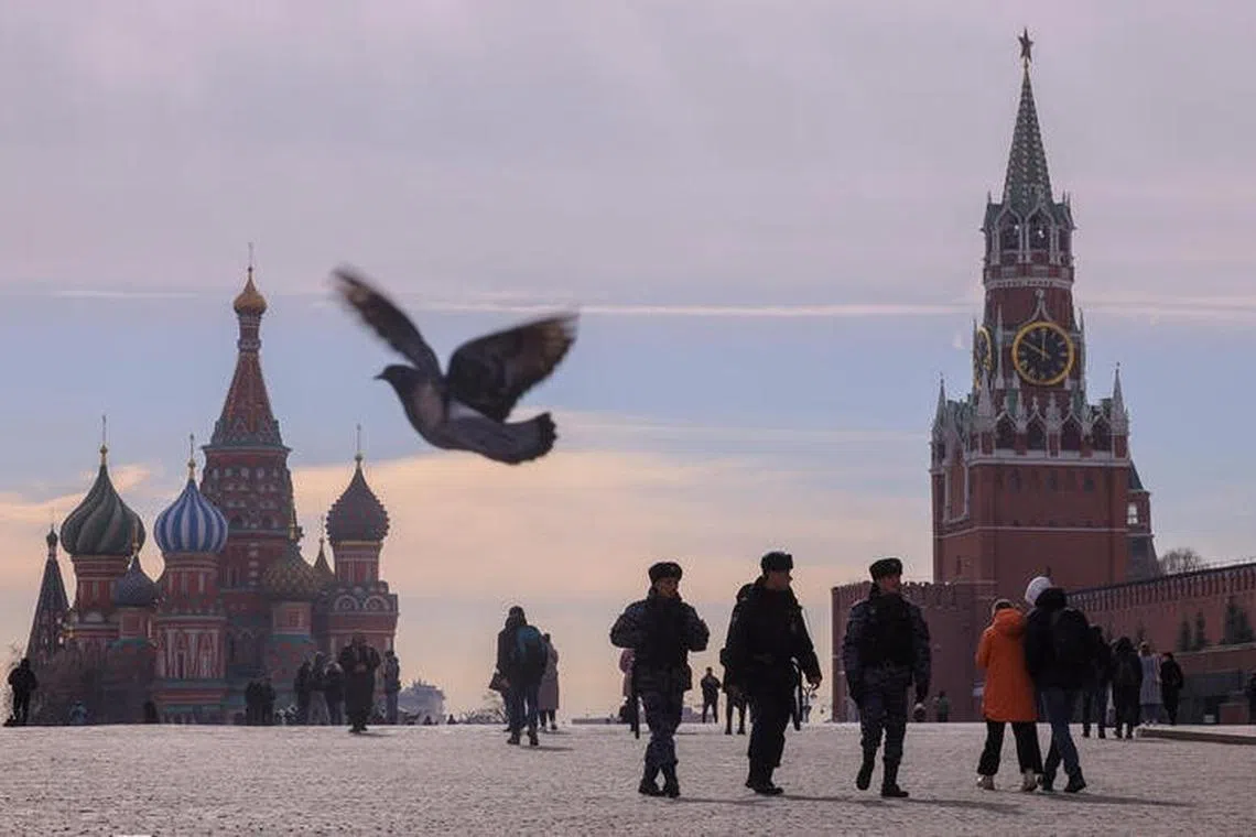 People, including Russian law enforcement officers, walk near St. Basil's Cathedral and the Kremlin's Spasskaya Tower in Red Square in central Moscow, Russia, March 20, 2023. REUTERS/Evgenia Novozhenina/files